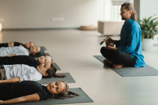 Children relax lying down to the sounds of a Tibetan bowl in the fitness room. Children's yoga.