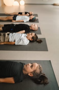 Children lying on the floor relax to the sounds of a Tibetan bowl. Children's yoga.