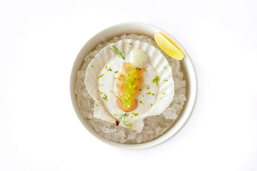 Scallop in sauce with flying fish caviar on a shell on ice isolated. High quality photo