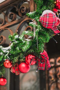 Stylish christmas fir branches with red and gold baubles on front of building holiday market in city street. Winter christmas street decor