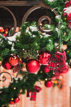 Stylish christmas fir branches with red and gold baubles on front of building holiday market in city street. Winter christmas street decor