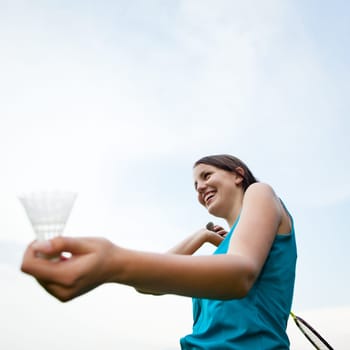 Pretty, young woman playing badminton in a city park on a lovely summer day (shallow DOF)