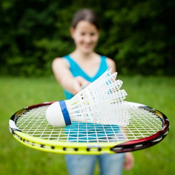 Pretty, young woman playing badminton in a city park on a lovely summer day (shallow DOF)