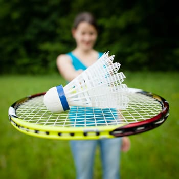 Pretty, young woman playing badminton in a city park on a lovely summer day (shallow DOF)