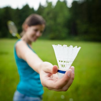Pretty, young woman playing badminton in a city park on a lovely summer day (shallow DOF)