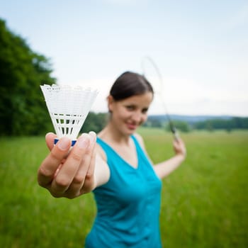 Pretty, young woman playing badminton in a city park on a lovely summer day (shallow DOF)