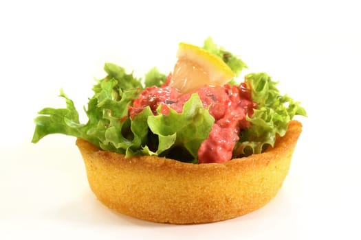 Corn tartlets with pollock salad against a white background