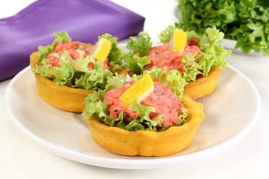 Corn tartlets with pollock salad against a white background