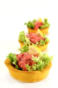 Corn tartlets with pollock salad against a white background