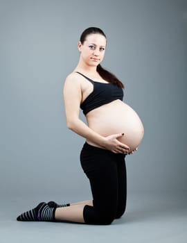 beautiful young pregnant woman with a gray background