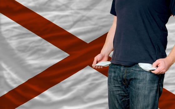 poor man showing empty pockets in front of american state of alabama flag