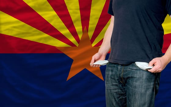 poor man showing empty pockets in front of arizona flag