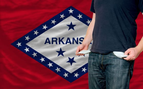 poor man showing empty pockets in front of arkansas flag