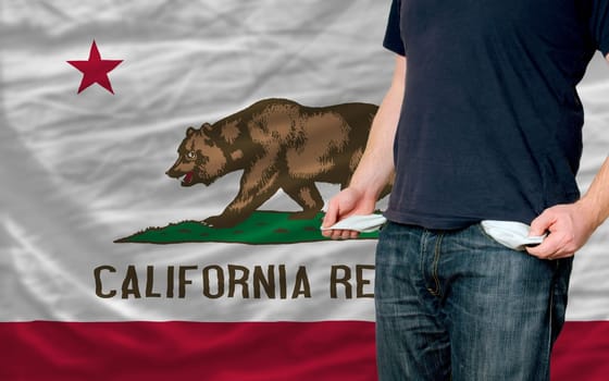 poor man showing empty pockets in front of california flag