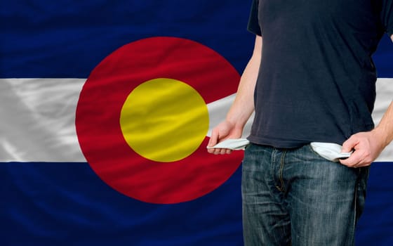 poor man showing empty pockets in front of colorado flag
