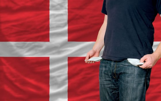 poor man showing empty pockets in front of denmark flag