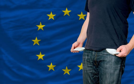 poor man showing empty pockets in front of europe flag