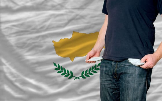 poor man showing empty pockets in front of cyprus flag