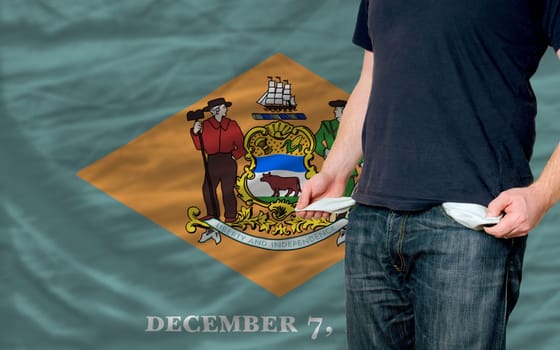 poor man showing empty pockets in front of delaware flag