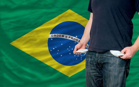 poor man showing empty pockets in front of brazil flag