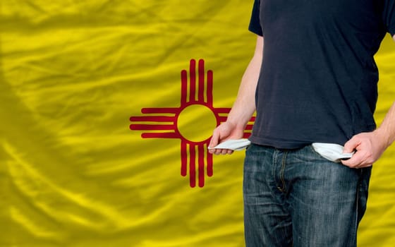 poor man showing empty pockets in front of american state of new mexicoflag