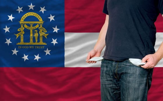 poor man showing empty pockets in front of georgia flag