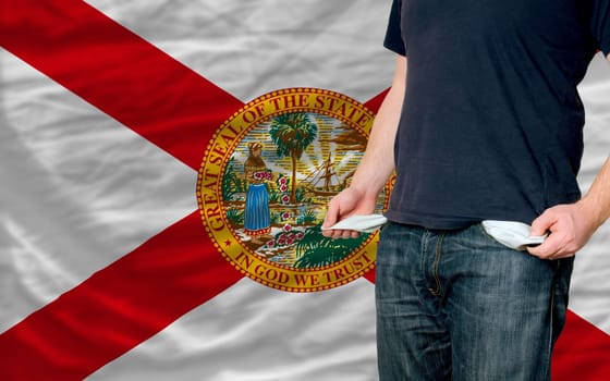 poor man showing empty pockets in front of florida flag