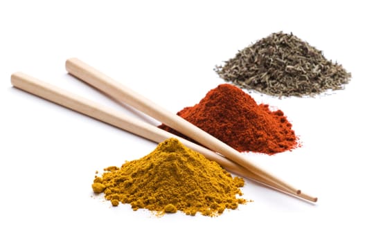 Heaps of various ground spices with chopsticks on white background