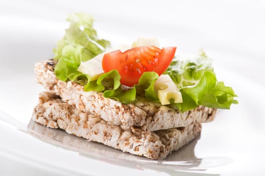 Healthy rice cake with salad, cheese and tomato close up