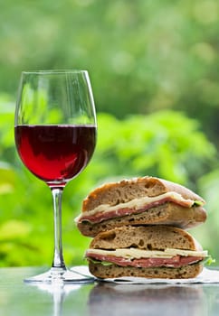 Fresh prosciutto sandwich and red wine outdoor close up