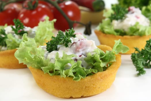 Corn tartlets with cheese salad against white background