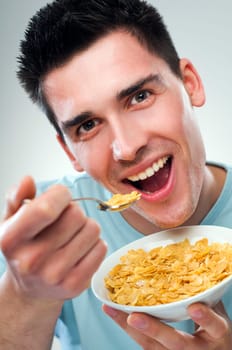 young man eating corn flakes close up