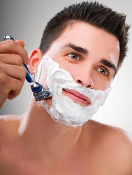 Young Man shaving with razor close up