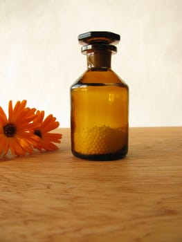 Calendula flowers and homeopathic globules in the medicine bottle