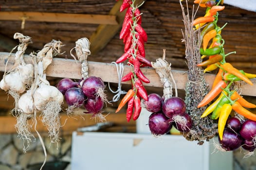 Garlic, onions and coloful peppers a wooden roof
