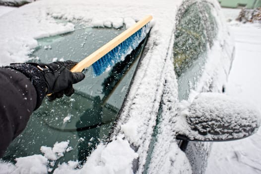 Removing snow from a car window using a brush