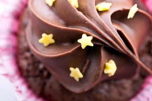 Close-up of chocolate cupcake frosting with yellow stars.   Angle from directly above.