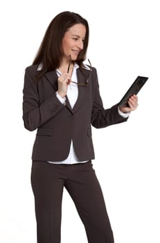 Attractive businesswoman holding and looking at tablet device against white background.