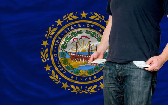 poor man showing empty pockets in front of american state of new hampshire flag