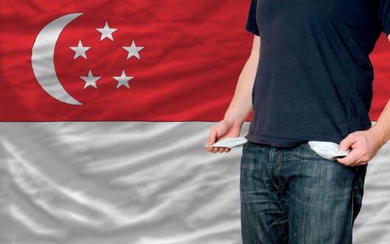 poor man showing empty pockets in front of singapore flag