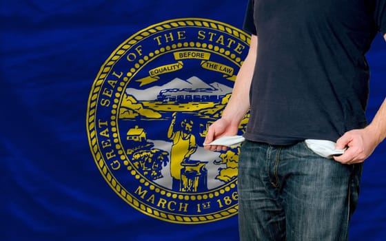 poor man showing empty pockets in front of american state of nebraska flag