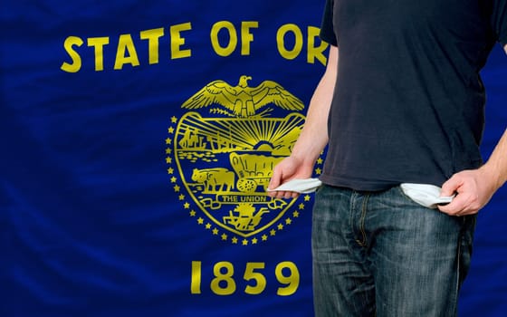 poor man showing empty pockets in front of american state of oregon flag
