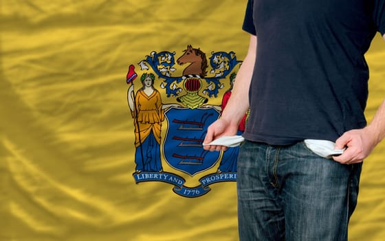 poor man showing empty pockets in front of american state of new yersey flag