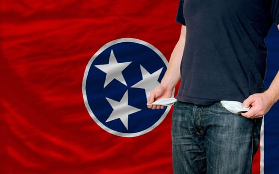 poor man showing empty pockets in front of american state of tennessee flag