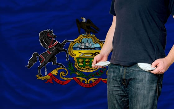 poor man showing empty pockets in front of american state of pennsylvania flag