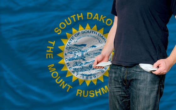 poor man showing empty pockets in front of american state of south dakota flag