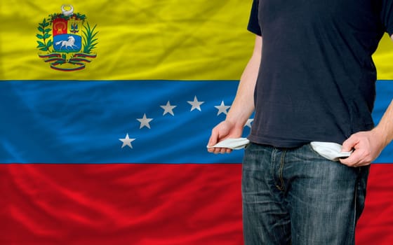 poor man showing empty pockets in front of venezuela flag