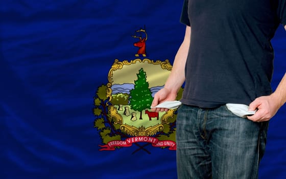 poor man showing empty pockets in front of american state of vermont flag
