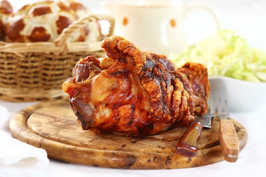 Grilled knuckle of pork with bread rolls and lettuce salad