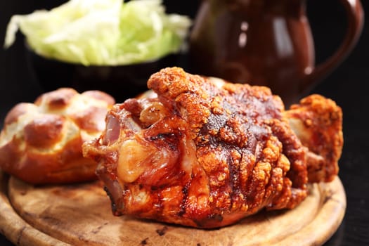 Grilled knuckle of pork with bread rolls and lettuce salad